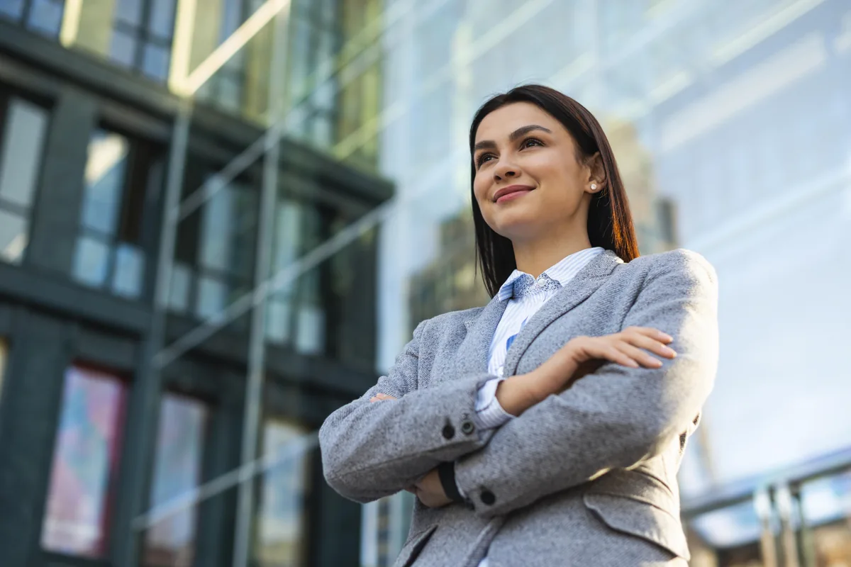 Mujer profesional con presencia firme mirando al horizonte — liderazgo femenino auténtico